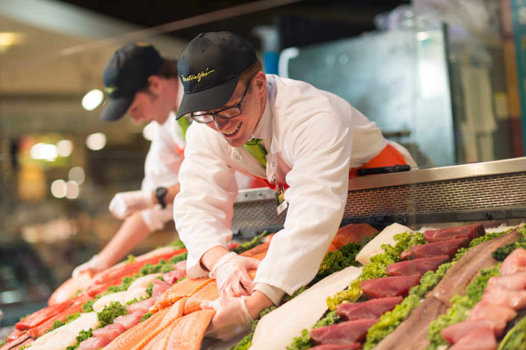 Person standing behind a seafood counter.