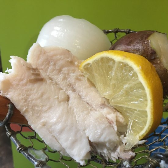 A traditional fish biol with lemons, potato's, and onions.