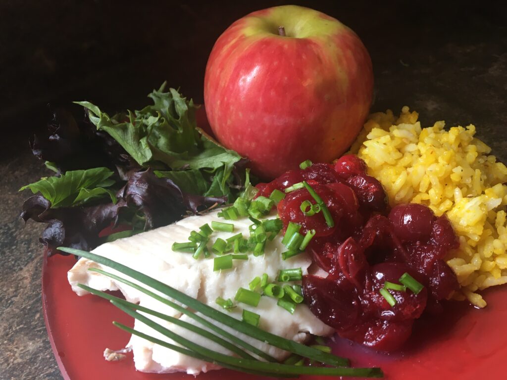 fish fillet with cranapple sauce, saffron rice, lettuce and and apple.