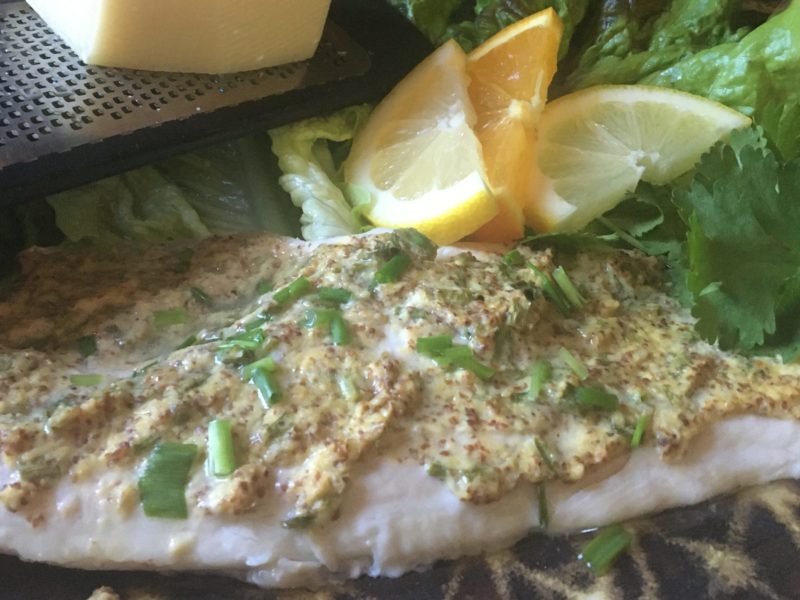 Baked fish with a parmesan spread served with cilantro, lemon, and lettuce.