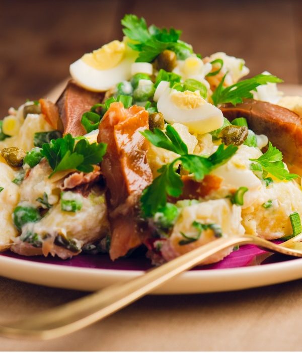A fish dish arranged with parsley, eggs, and peas drizzled in vinaigrette.