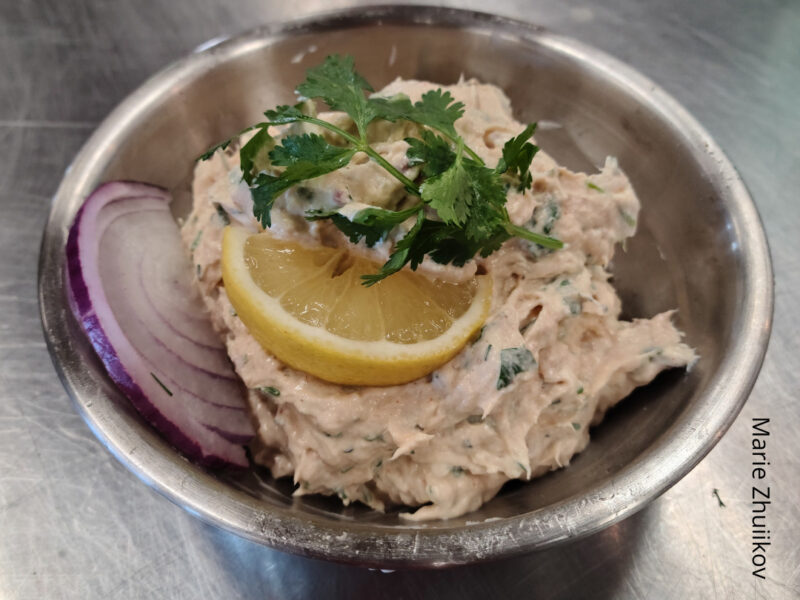 fish spread in a metal bowl with lemon, parsley and red onion garnish