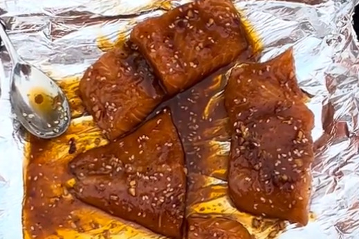 A spoon and four chunks of salmon in sesame-ginger marinade.